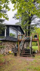 a house with a deck and stairs in front of it at Falcon Retreats in Sharbot Lake