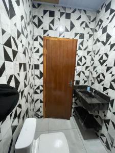 a bathroom with a toilet and a wooden door at Apartamento Açaí in Vilhena