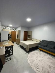 a bedroom with a bed and a couch and a table at Apartamento Açaí in Vilhena