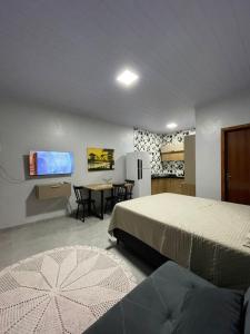 a bedroom with a bed and a table and a tv at Apartamento Açaí in Vilhena