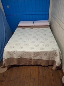 a bed with a blanket on top of a wooden floor at Siio do bambu in Joinville