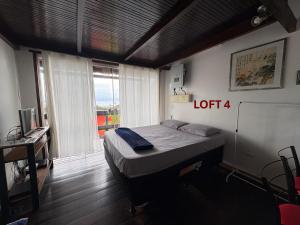 a bedroom with a bed in a room with a window at Mi Casa Su Casa Lofts in Abraão