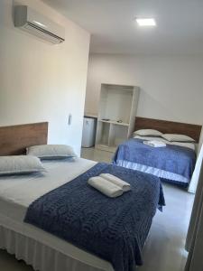 two beds in a room with towels on them at Pousada casa da amizade in Penha