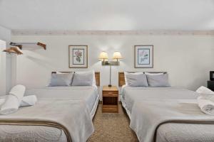 two beds in a hotel room with white walls at Eagle Motel Suite 112 in Manitou Springs