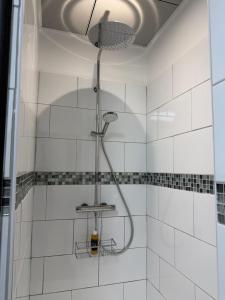 a shower in a white tiled bathroom at Casa Théodore in San-Nicolao