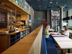 two women sitting at a counter in a restaurant at ibis budget Blankenberge in Blankenberge
