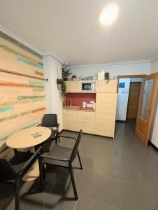 a room with a table and chairs and a kitchen at Alojamiento La Ballena in Santoña