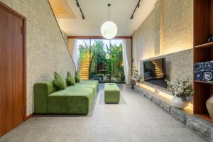 a living room with a green couch and a fireplace at U Villas - Tropical Views Luxury Stay with Pool & Workspace in Ungasan