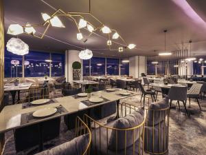 a restaurant with tables and chairs and lights at Mercure Hangzhou Qianjiang in Hangzhou