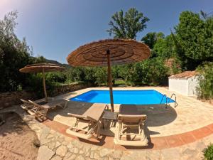a pool with two umbrellas and two chairs and a swimming pool at Molino del Caracol in Benaoján