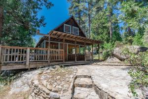 a cabin in the woods with a large deck at Harmony Hideaway Hammocks Creek Sounds in Shaver Lake