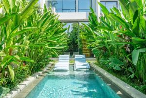 a pool in the middle of a garden with palm trees at U Villas - Tropical Views Luxury Stay with Pool & Workspace in Ungasan