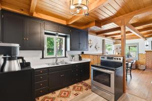 a kitchen with black cabinets and a stove at Harmony Hideaway Hammocks Creek Sounds in Shaver Lake
