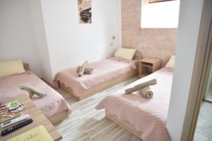 a room with three beds with pink sheets and a table at Apartment Friends in Veles