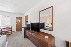 a living room with a television on a dresser with a mirror at Eagle Motel Suite 226 in Manitou Springs +10 photos