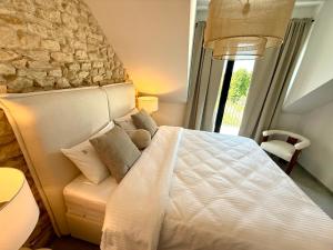 a bedroom with a white bed and a stone wall at BOGORIA Apartments in Uniejow