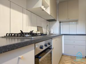 a kitchen with white cabinets and a stove top oven at Harbor Room at City Center Gdynia & Seaside in Gdynia +22 photos