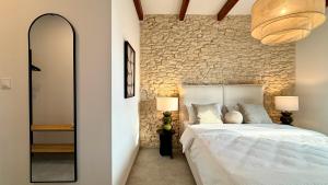 a bedroom with a white bed and a stone wall at BOGORIA Apartments in Uniejow