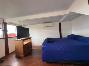 a bedroom with a blue bed and a tv at Mi casa Su casa Lofts - LOFT 5 in Angra dos Reis