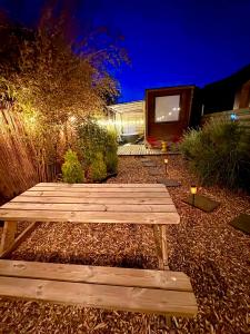 a wooden bench sitting in a garden at night at Romantic Tiny House with Private Jacuzzi and Garden between Amsterdam Haarlem and Schiphol Airport in Vijfhuizen +62 photos