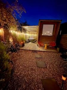 a backyard with a wooden deck with red chairs at Romantic Tiny House with Private Jacuzzi and Garden between Amsterdam Haarlem and Schiphol Airport in Vijfhuizen