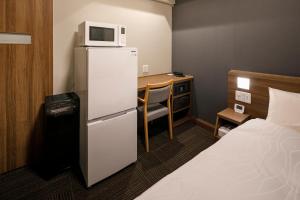 a small room with a desk and a refrigerator with a microwave at Dormy Inn Express Toyohashi in Toyohashi