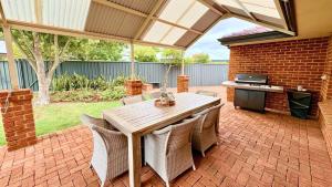 a patio with a wooden table and chairs and a grill at Coastal Haven on Sandpiper in Broadwater