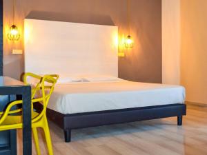 a bedroom with a bed and a table and a yellow chair at ibis styles Trani in Trani