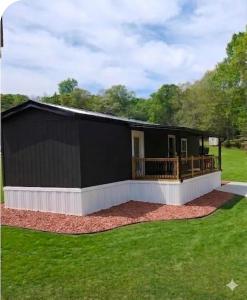 a large black building with a deck on a yard at Tiny Home with Grill Laundry Deck Desk in Phenix City