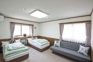 a bedroom with two beds and a couch at Wolke Lodge in Shinano