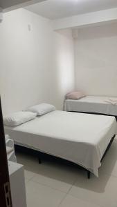 two beds are in a room with a white wall at Pousada Recanto Bella Vista in Saubara
