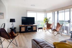 a living room with chairs and a flat screen tv at Rundle & Salt in Ulladulla