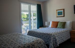a bedroom with a bed and a sliding glass door at Motel de l'Anse a l'Eau in Tadoussac