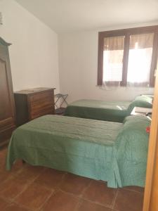a bedroom with two beds and a dresser and a window at Agriturismo Punta Su Cunventu in Narcao +4 photos