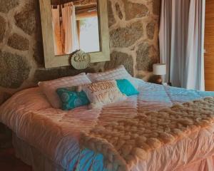 a bedroom with a large bed with a stone wall at Huellas de Berna in Villa Berna