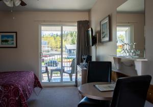 a hotel room with a bed and a table and a balcony at Motel de l'Anse a l'Eau in Tadoussac