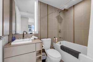 a bathroom with a toilet and a sink and a tub at Altitude Residences in Toronto +18 photos