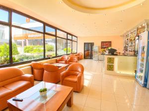 a waiting room with orange chairs and tables and windows at Hotel Rostov in Pleven