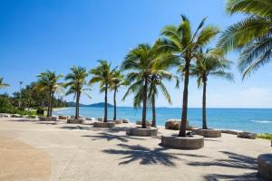 a row of palm trees on a beach with the ocean at Sea Sand Sun Condominium in Ban Bang Nok