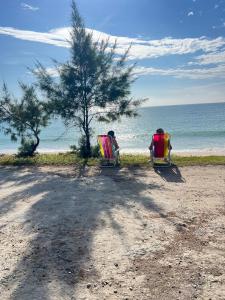 two people sitting in lawn chairs on the beach at Casa com Piscina Privativa e Área Gourmet in Rio das Ostras +50 photos