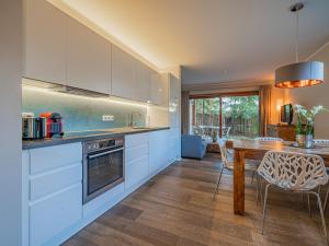 a kitchen with white cabinets and a wooden table at Kitz Apartments Top 6 in Kitzbühel