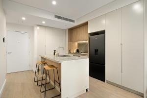 a kitchen with white cabinets and a black refrigerator at Stylish CBD Apartment with Courtyard and Parking in Newcastle