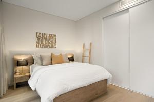 a bedroom with a bed with white sheets and pillows at Stylish CBD Apartment with Courtyard and Parking in Newcastle