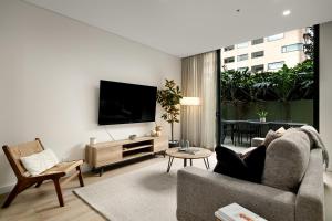 a living room with a couch and a flat screen tv at Stylish CBD Apartment with Courtyard and Parking in Newcastle