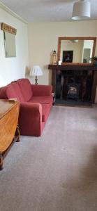 a living room with a red couch and a fireplace at Lee Cottage Appledore in Appledore