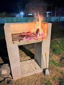 a fire pit with meat on a grill at Cabaña El Refugio in Lago Puelo