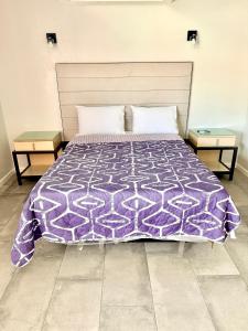a bed with a purple comforter and two tables at Rocky Inn Motel in Lynwood