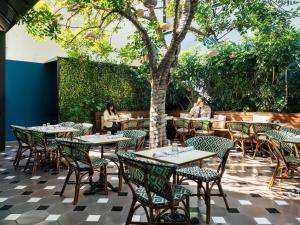 an outdoor patio with tables and chairs and a tree at Palihotel Culver City in Los Angeles