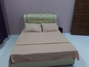 a bed with a green headboard in a room at IA Tiny House in Kampong Sura Tengah