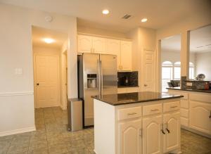 a kitchen with white cabinets and a stainless steel refrigerator at Pet friendly Spacious 4 Bedroom home with large, fenced backyard, located to DFW airport, restaurants and shops in Irving